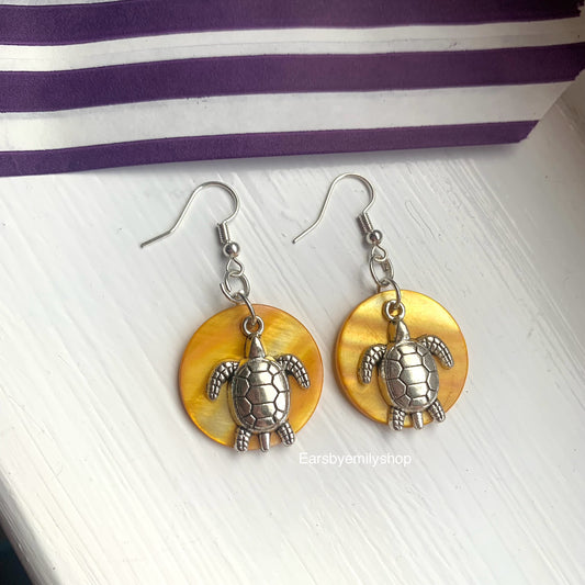 Cool beach inspired silver turtle handmade drop dangle earrings on a yellow sea shell disc. Perfect for summer