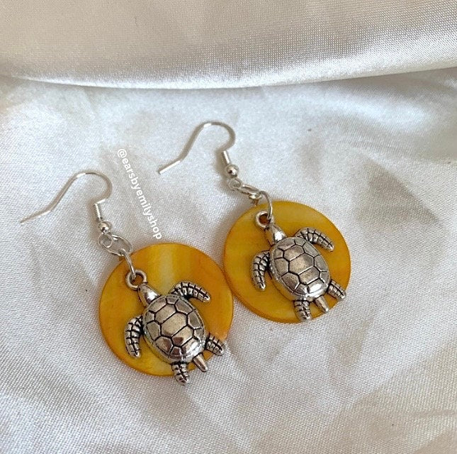 Cool beach inspired silver turtle handmade drop dangle earrings on a yellow sea shell disc. Perfect for summer