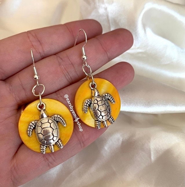 Cool beach inspired silver turtle handmade drop dangle earrings on a yellow sea shell disc. Perfect for summer