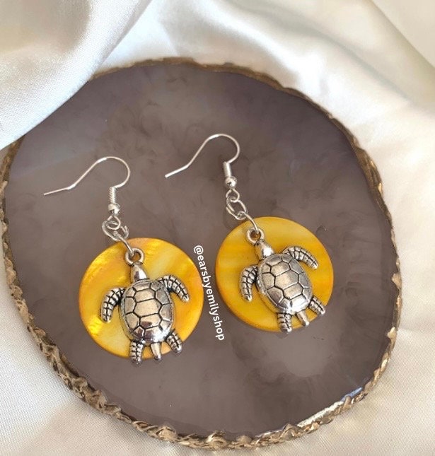 Cool beach inspired silver turtle handmade drop dangle earrings on a yellow sea shell disc. Perfect for summer