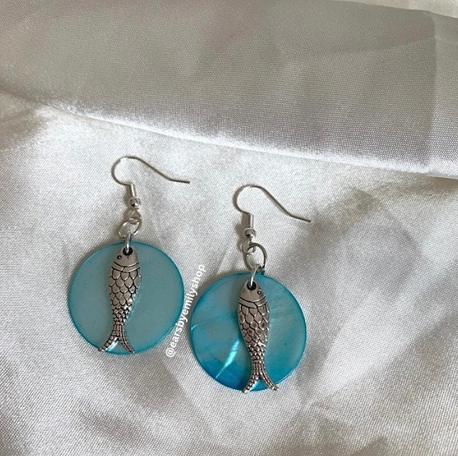 Cool beach inspired silver fish handmade drop dangle earrings on a blue sea shell disc